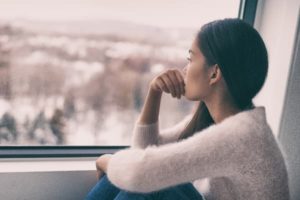 Woman sitting by window, depression