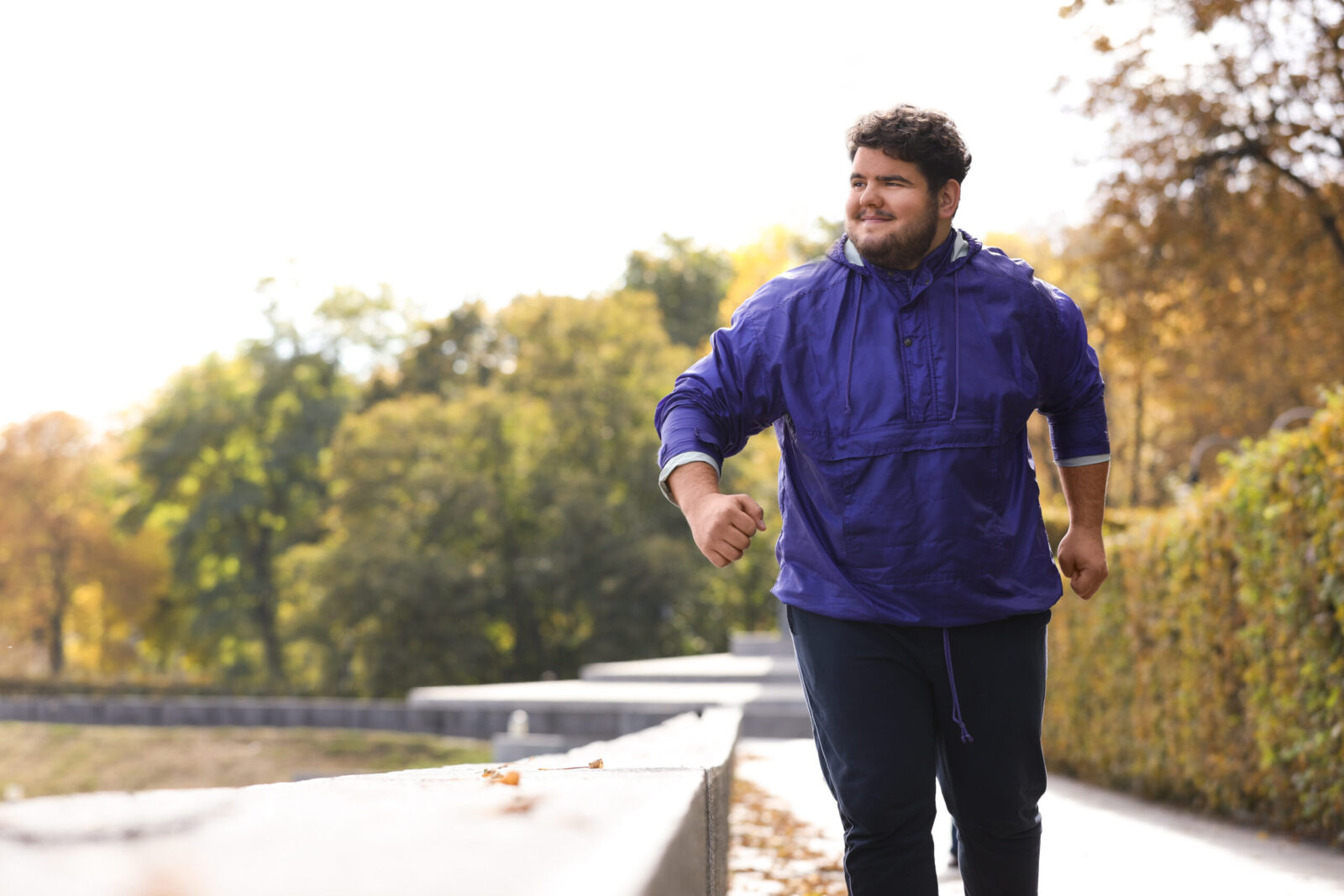 Adult jogging outdoors in a park while working toward weight loss